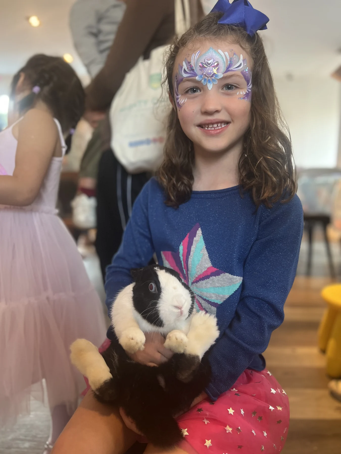 Child with face paint meeting a rabbit at a Magical Guy party